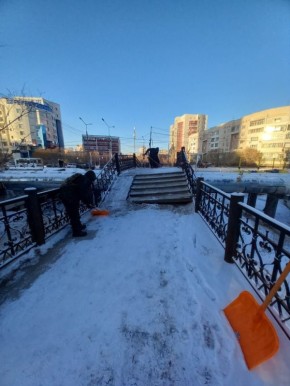 Дворники тщательно чистят снег на мосту — безопасность и чистота на первом месте!